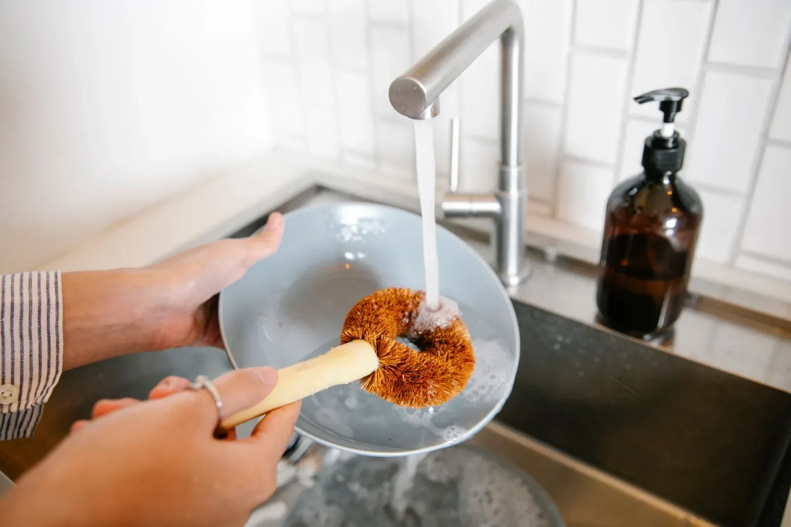 Washing a plate with a brush at the kitchen sink